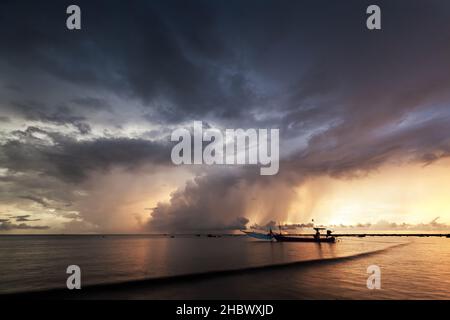 Bel tramonto e tempesta di pioggia con le barche di gamberi Opossum ormeggiate al porto sulla spiaggia di Pakarang Phang Nga, Thailandia Foto Stock