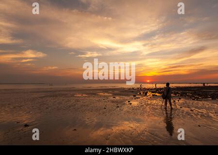 Fotografo amatoriale femminile che scatta foto al tramonto sulla spiaggia al crepuscolo Foto Stock