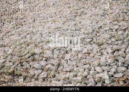 Pietre di granito dietro una griglia di metallo per rinforzare la pendenza. Pietre dietro il filo. Struttura grigia. Costruzione. Foto Stock