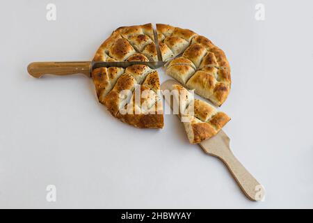 Pane del Ramadan turco a fette triangolare, pelo su superficie bianca con spatola e coltello. Foto Stock