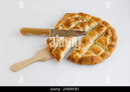 Pane del Ramadan turco a fette triangolare, pelo su superficie bianca con spatola e coltello. Foto Stock