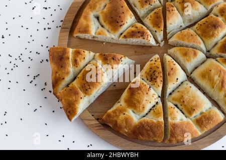 Pane ramadan a fette triangolare, pide sul piatto di legno con semi di sesamo e nigella, vista dall'alto. Foto Stock