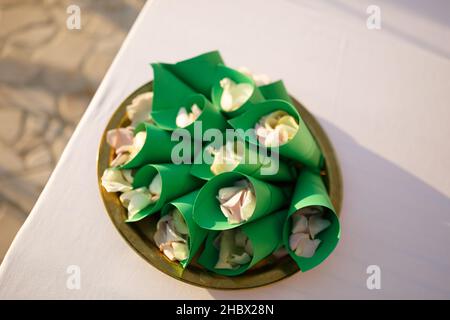 I petali di rosa si trovano in fogli di carta piegati su un piatto Foto Stock