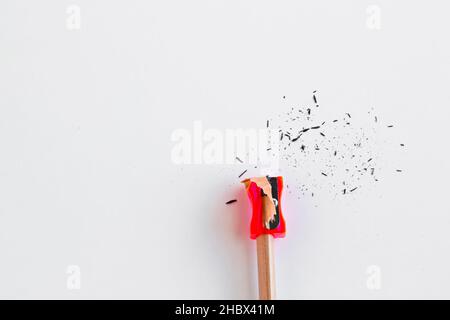 Matita in legno naturale con affilatore rosso sulla superficie bianca.immagine concettuale dell'educazione. Foto Stock