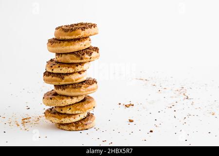 Anelli tradizionali turchi di Sesamo Kandil Simidi impilati sulla superficie bianca con un grande spazio di copia Foto Stock