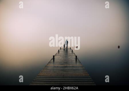 Bella nebbia suggestiva mattina nel Lake District con padre e figlio Foto Stock