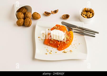 Tradizionale dessert turco di zucca, cremoso, kayak e noci tritate guarnendo in piatto con posate. Foto Stock