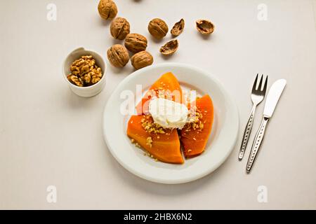 Tradizionale dessert turco di zucca, cremoso, kayak e noci tritate guarnendo in piatto con posate. Foto Stock