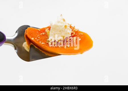 Una fetta di dessert tradizionale di zucca turca con panna e noci su una spatola metallica sulla superficie bianca Foto Stock