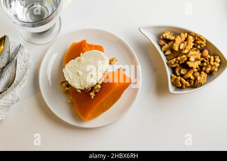 Tradizionale dessert turco di zucca, nel piatto bianco con noce e acqua. Vista dall'alto Foto Stock