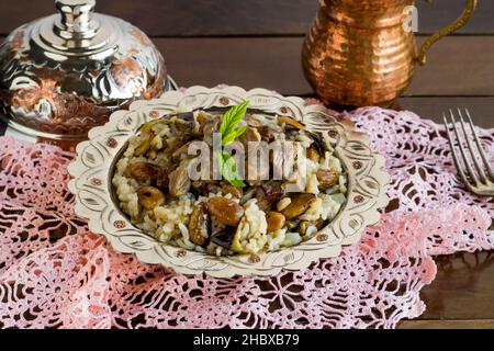 Tradizionale turco Islamico Festival, cibo con brasato di carne, Kavurma e pilaff in vaso d'annata di rame su bianco con bevanda e forchetta Foto Stock