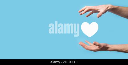 Maschio mano che tiene il cuore , come icona su sfondo blu. Gentilezza, carità, puro amore e compassione concept.Banner con spazio copia. Foto Stock