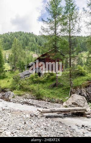 Un antico mulino ad acqua in legno a ruscello in Val di Morins. Longiaru, Italia (foto verticale) Foto Stock