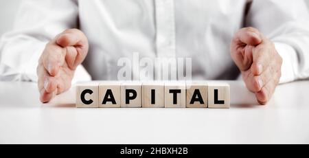Mano dell'uomo d'affari che mostra la parola capitale su cubi di legno. Concetto di capitale di rischio aziendale. Foto Stock