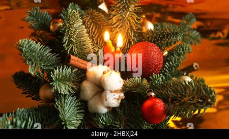 Decorazione di Natale con candele. Composizione di rami di albero di Natale, giocattoli e candele brucianti su sfondo dorato. Foto Stock