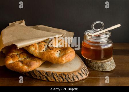 Pane tradizionale turco Ramadan, Pide in carta kraft su tavola di legno con miele. Foto Stock