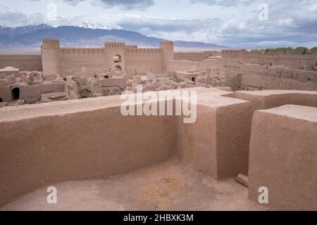 Panorama di stradine strette e mura dell'antica città persiana costruita con mattoni di fango. Cittadella di Rayen, Mahan, Iran, con il massiccio di Hezar sullo sfondo. Foto Stock