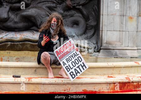 Protesta della ribellione animale seduta nella fontana reale, tenendo un cartello che dice Animal Agriculture A Royal Bloodbath 2021 Foto Stock