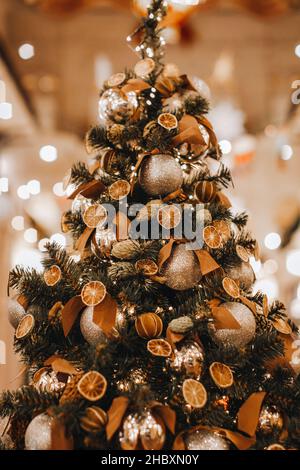 Interessante albero di Natale creativo decorato con arance secche, coni di pino e mandarini. Dettagli accoglienti. Stagione invernale in vacanza vigilia. Postc. Verticale Foto Stock