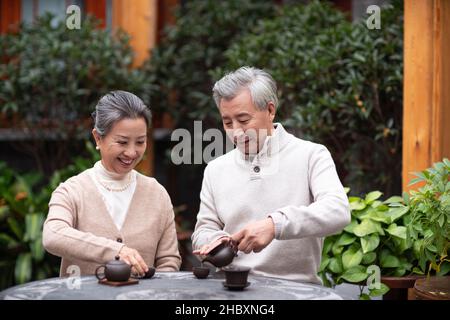 La vecchia coppia beve il tè e chiacchierava nel cortile Foto Stock