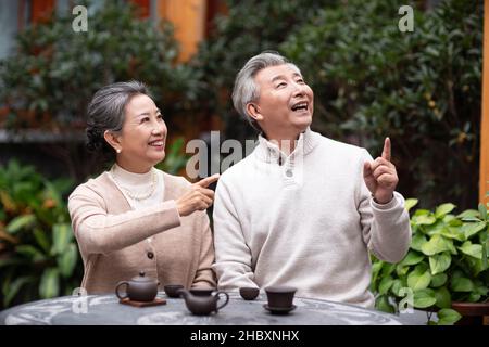 La vecchia coppia beve il tè e chiacchierava nel cortile Foto Stock