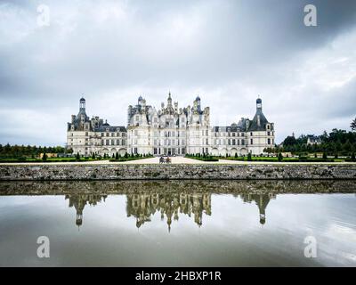 Vista grandangolare del Castello di Chambord nella valle della Loira, con i suoi giardini, giorno nuvoloso, riflessione d'acqua, Francia Foto Stock