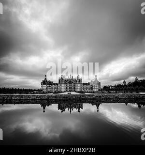 Vista grandangolare del Castello di Chambord nella valle della Loira, con i suoi giardini, giorno nuvoloso, riflessione d'acqua, Francia Foto Stock