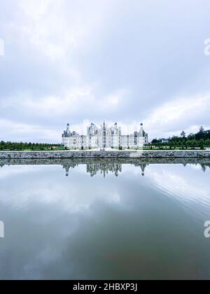 Vista grandangolare del Castello di Chambord nella valle della Loira, con i suoi giardini, giorno nuvoloso, riflessione d'acqua, Francia Foto Stock