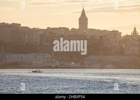 Pescatori in barche da pesca e traghetti di linea della città nel Bosforo all'alba in inverno mattina a Istanbul, Turchia il 21 dicembre 2021. Foto Stock