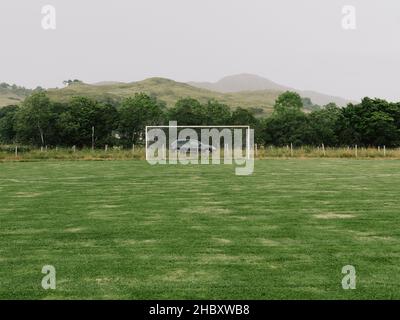 Un'auto unica dietro un campo di calcio vuoto e gol nel remoto paesaggio rurale delle West Highland di Glenelg, Scozia Regno Unito - vuoto paesaggio di calcio nessuno folla Foto Stock