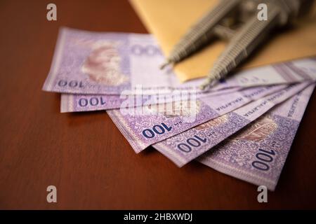Primo piano di un involucro pieno di documenti o contratti con denaro sotto di esso. Venalità, tangenza, concetto di corruzione. Foto Stock