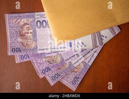 Primo piano di un involucro pieno di documenti o contratti con denaro sotto di esso. Venalità, tangenza, concetto di corruzione. Foto Stock