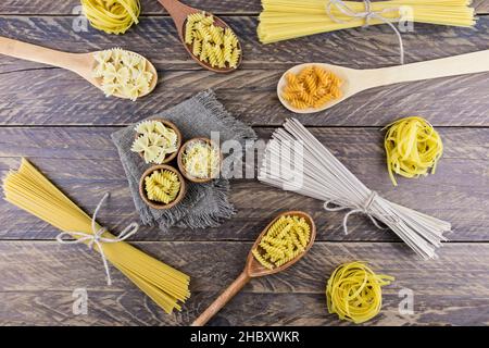 una varietà di tipi e forme di pasta secca su un tavolo di legno villaggio. pasta sfondo. vista dall'alto Foto Stock