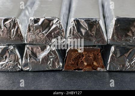 Tavolette di cioccolato fondente con noci tritate, avvolte in foglio Foto Stock