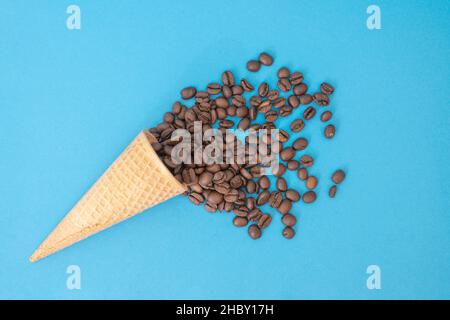 cono gelato con chicchi di caffè isolati su sfondo blu Foto Stock