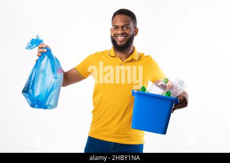 Black Man che tiene il sacco di rifiuti e la scatola su sfondo bianco Foto Stock