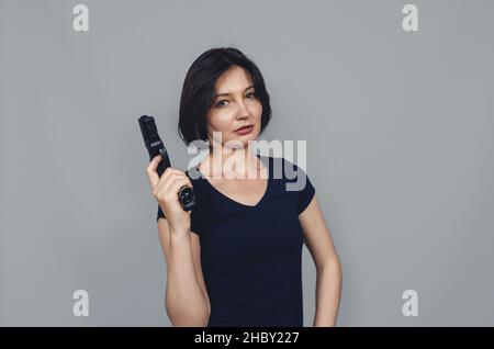 Pistola nelle mani di bella donna. Aspetto pensivo. Foto Stock