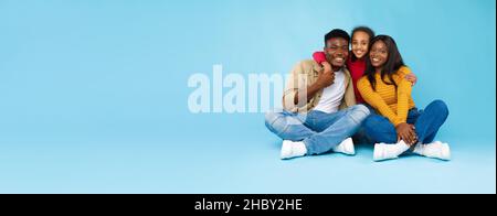 Uomo, donna e ragazza afro-americani seduti a terra Foto Stock
