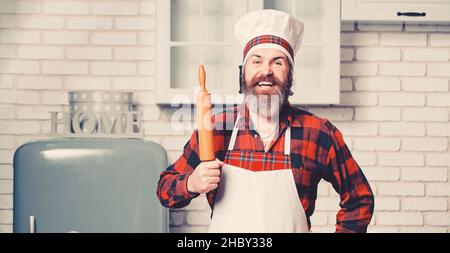 Lo chef cuoco con barba tiene una spilla su una cucina bianca. Foto Stock