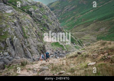 Langdale Cumbria, vista di una coppia matura che discende Stickle Ghyll, un percorso impegnativo che conduce ai Langdale Pikes, Lake District, Cumbria, Regno Unito Foto Stock