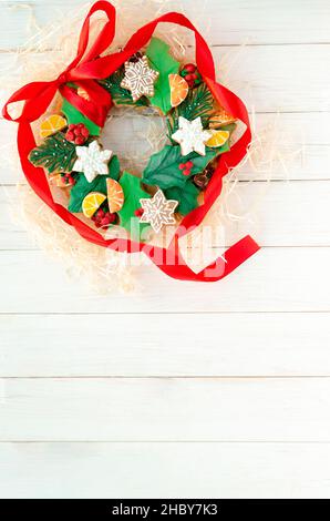 Pan di zenzero di Natale sotto forma di corona di Natale si trova su uno sfondo bianco di legno. Biglietto di Natale Foto Stock