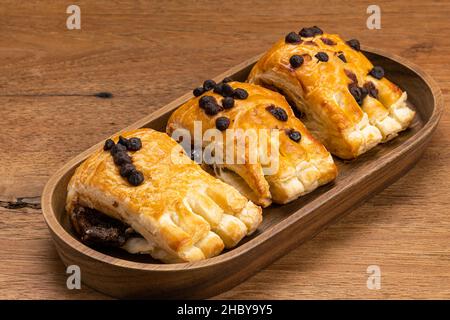 Dolce pasticceria danese fatta in casa con crema di cioccolato farcitura con gocce di cioccolato in vassoio di legno su tavola di legno. Foto Stock