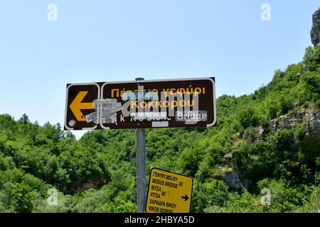 Grecia, Epiro, segnaletica per varie destinazioni nel distretto di Zagori aka Zagorohoria danneggiato con adesivi Foto Stock