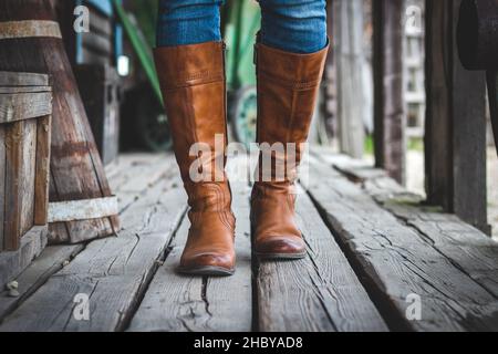 Camminando su pavimento in legno con stivali in pelle su vecchio ranch retrò. Stile cowboy. Foto Stock