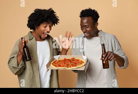 Ritratto di due eccitati Black Friends Holding bottiglie di birra e pizza Foto Stock