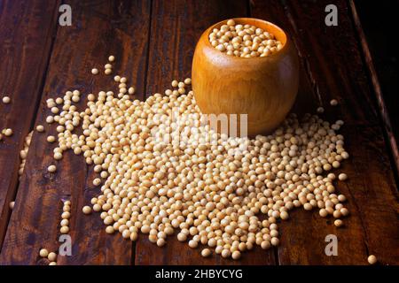 fagioli di soia crudi e freschi all'interno di una ciotola di legno su un rustico tavolo di legno Foto Stock