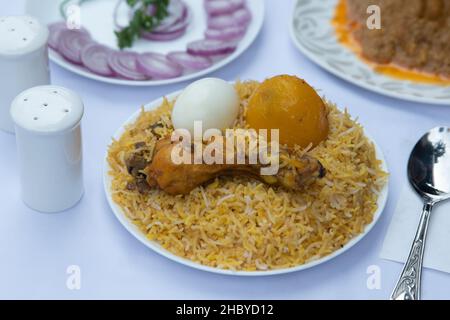 Primo piano del biryani di pollo con uova e cipolle affettate servite in un piatto bianco per il gusto................ Foto Stock