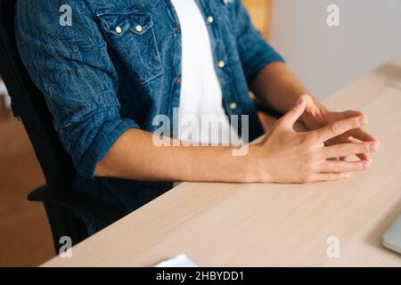 Primo piano cropped le mani del colpo di uomo d'affari nervoso non riconoscibile che si siede in postura chiusa, tensione o anticipazione nervosa, determinazione. Foto Stock
