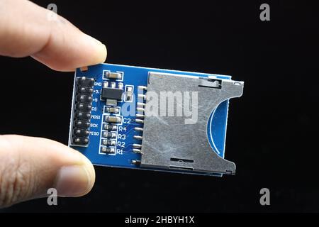 Modulo lettore di schede micro SD per progetti elettronici tenuti in mano isolati su sfondo nero Foto Stock