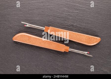 Due coltelli da cucire per tagliare i fili su una pietra ardesia, primo piano, vista dall'alto. Foto Stock
